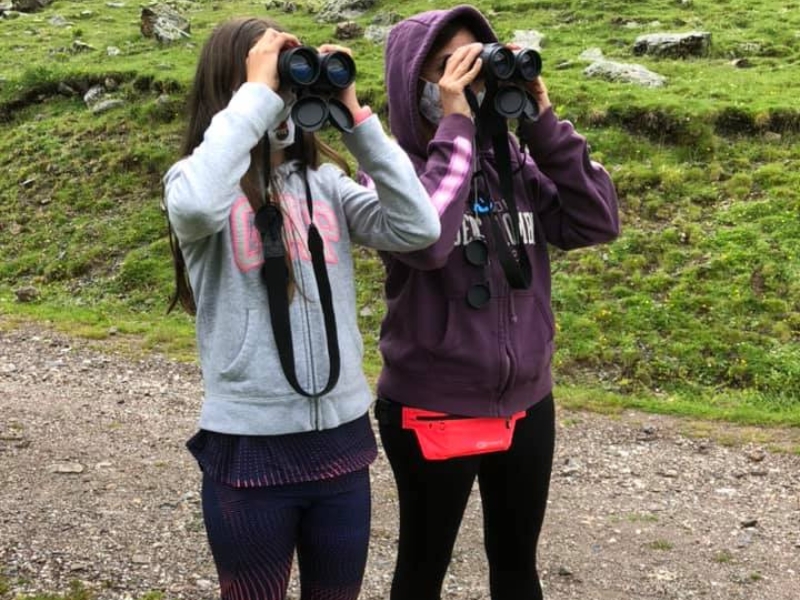 dos chicas mirando a través de los prismáticos buscando aves rapaces pirineos