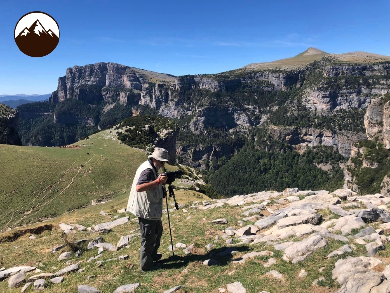 Adulto en la alta montaña buscando pájaros del Pirineo con un telescopio
