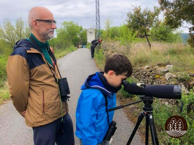 Padre observando a su hijo mirar por un telescopio en busca de Aves del Pirineo